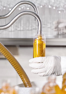 Mão de um cientista segurando tubo de ensaio com óleo em teste